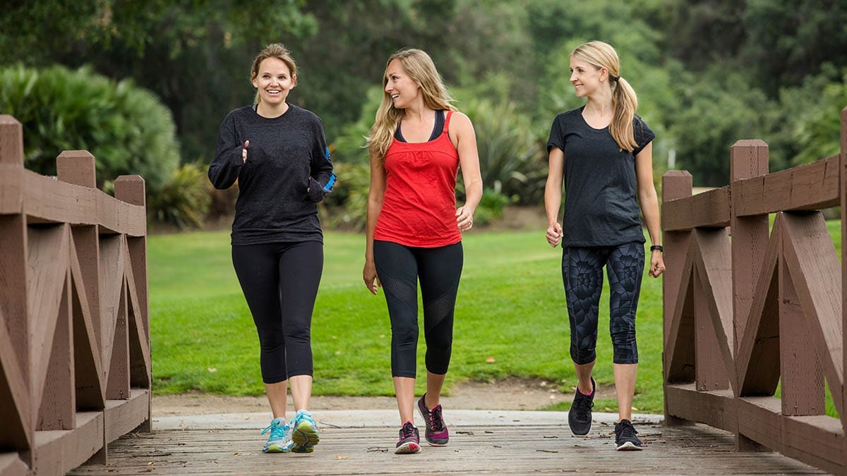 Group women in their 30s walking together in the outdoors.