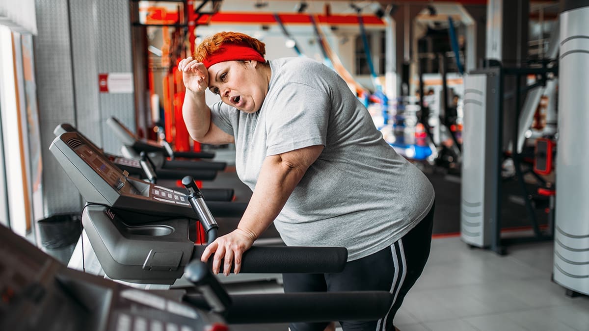 Overweight woman running on a treadmill in gym
